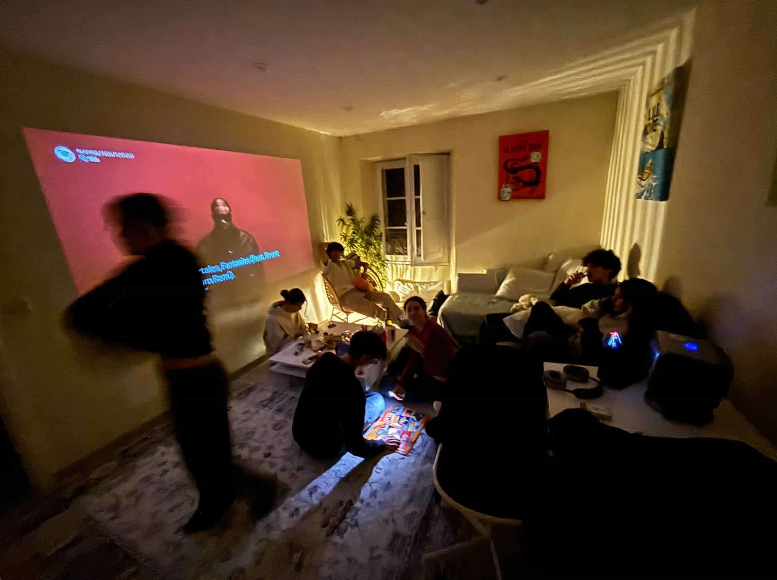 A friend group hanging out around a projector at a house party